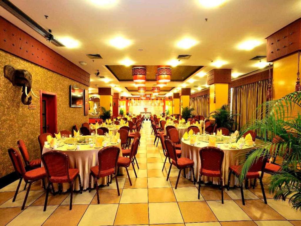 a dining room with tables and chairs in a restaurant at Kunming Guihua Hotel in Kunming