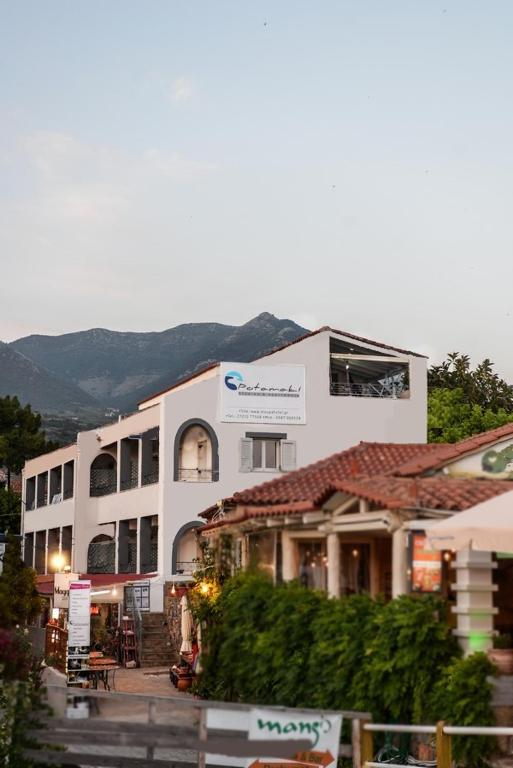 a large white building with a mountain in the background at Potamaki Studios & Apartments in Stoupa