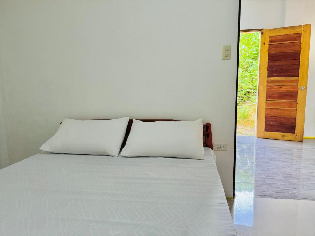 ein Bett mit zwei weißen Kissen in einem Zimmer in der Unterkunft Narra Villas Soft Opening Promo Get Entire Unit in General Luna