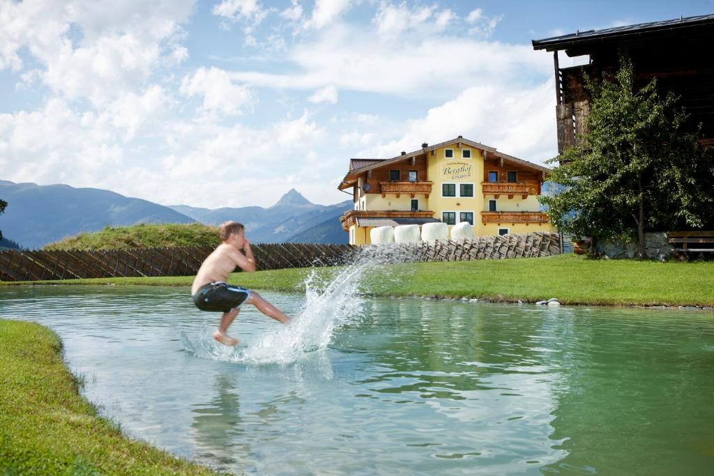 a young man is jumping into a pond at Appartements Luegeck in Hollersbach im Pinzgau