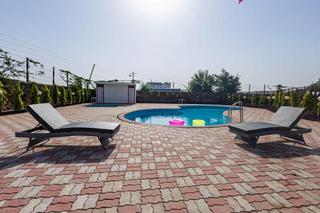 a patio with two chairs and a swimming pool at De Vivendi Farm- A Rural Luxury Farmhouse Getaway in Bahora
