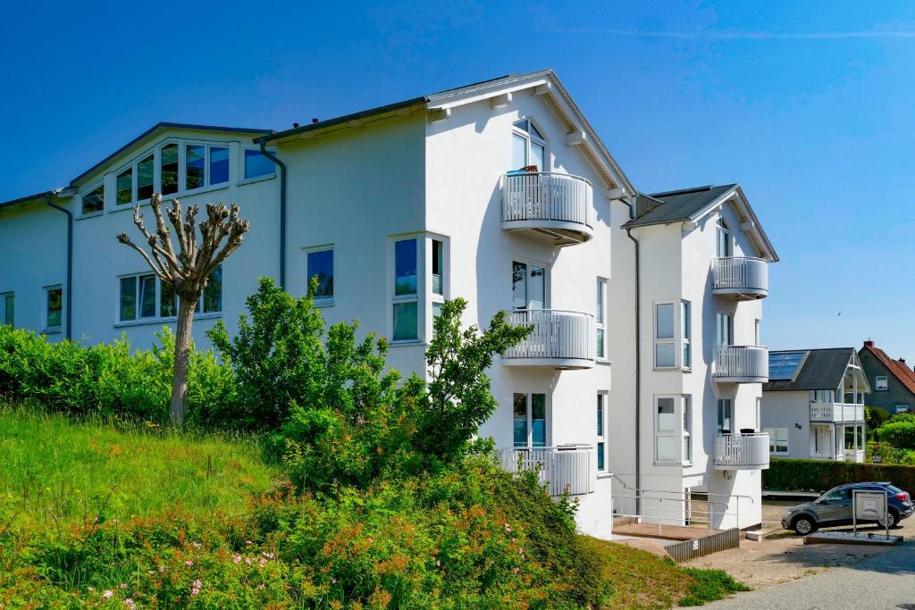 a white building with balconies and a car parked in front at Villa Monika Steuerbord 5 in Sassnitz
