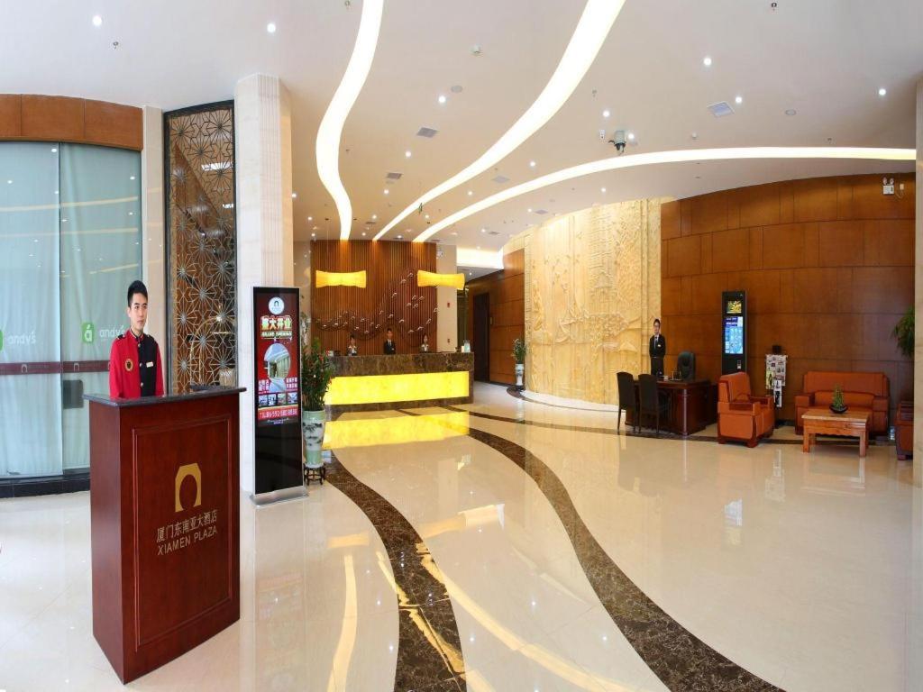 a man standing at a podium in a lobby at Xiamen Plaza Hotel in Xiamen