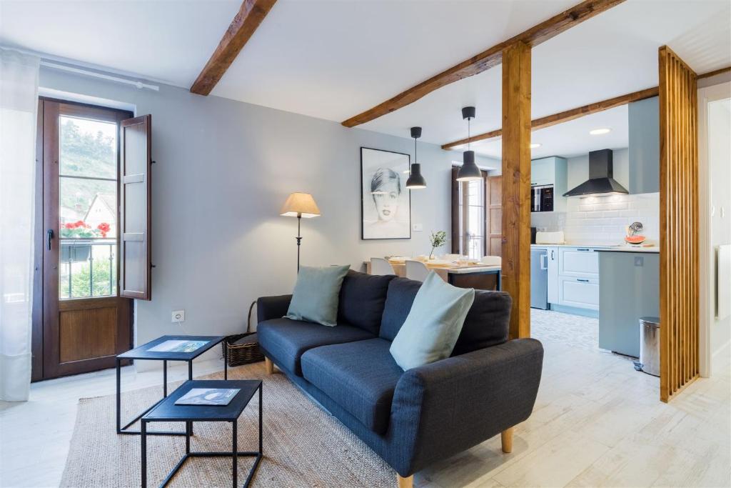 a living room with a blue couch and a kitchen at La Gaitona d'Aller - Cabañaquinta in Aller