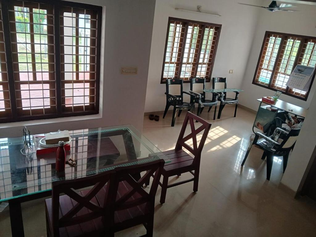 Una sala de estar con una mesa de cristal y sillas. en Staycation Homestay, en Ernakulam