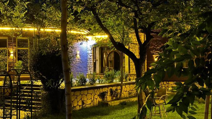 Una casa con una cerca de piedra y un edificio con luces. en Afghania Guest House, en Kabul