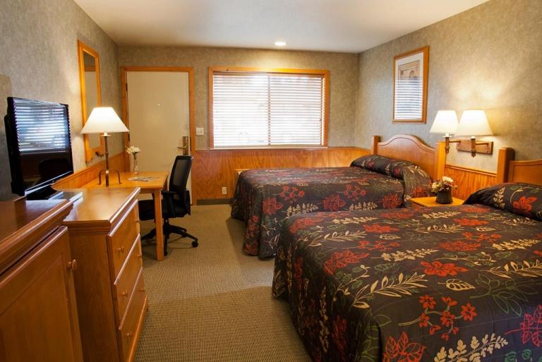 a hotel room with two beds and a desk at Poulsbo Inn & Suites in Poulsbo