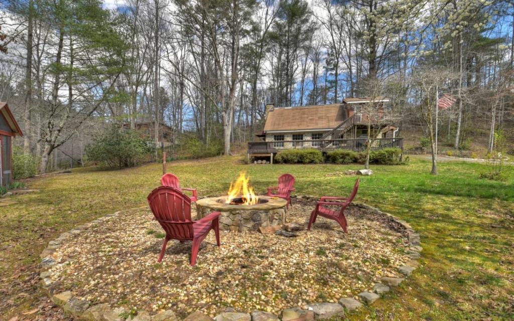 3 Stühle, die um eine Feuerstelle in einem Hof sitzen in der Unterkunft Knotty Creek Retreat - Creek Access, Outdoor Firepit + Hot Tub with Creek Views! in Morganton