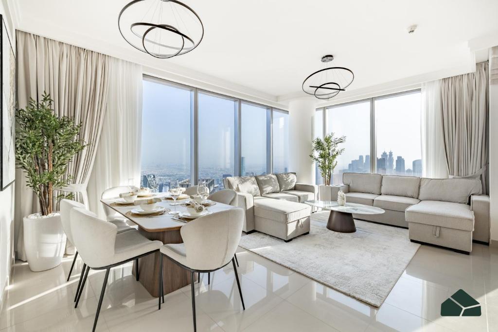 una sala de estar con muebles blancos y ventanas grandes. en High Floor 2BR with Full Burj View by BMS, en Dubái