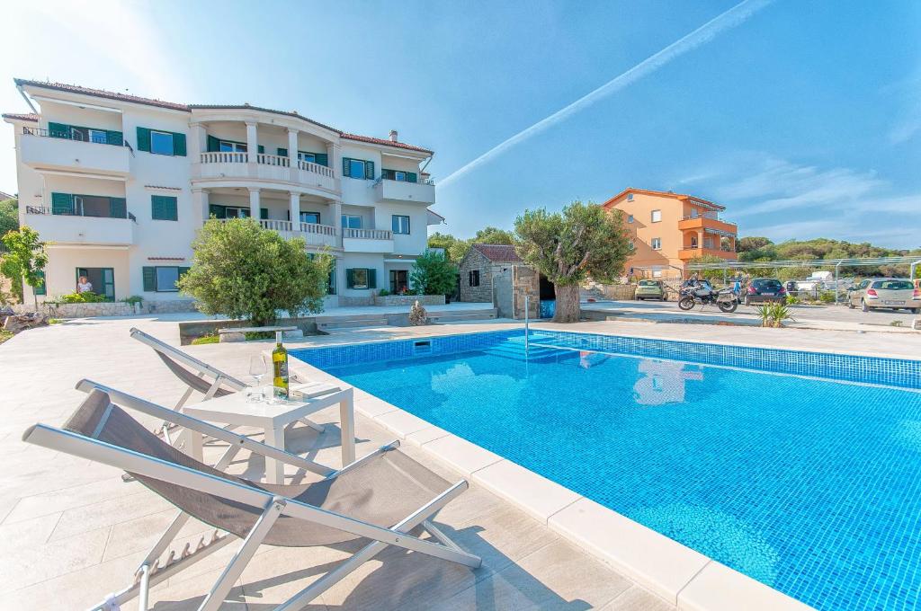 a swimming pool with two chairs next to a building at Apartments Ruzmarin in Lun