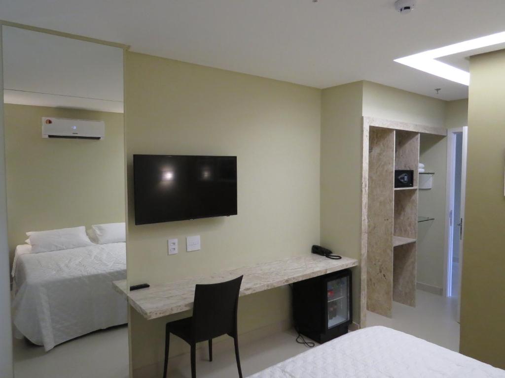 a bedroom with a desk with a tv on the wall at Uchôa Teresina Hotel in Teresina