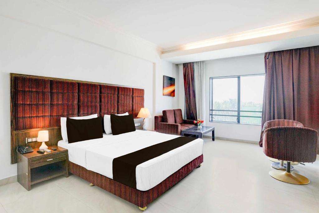 a bedroom with a large bed and a large window at Super Townhouse Bharuch Railway Station in Bharuch