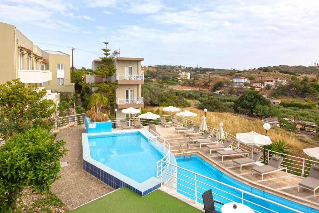 a swimming pool with lounge chairs and a hotel at Pelagia Bay Hotel in Agia Pelagia