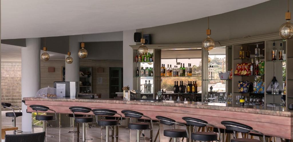 a bar with a bunch of stools in a room at Pelagia Bay Hotel in Agia Pelagia
