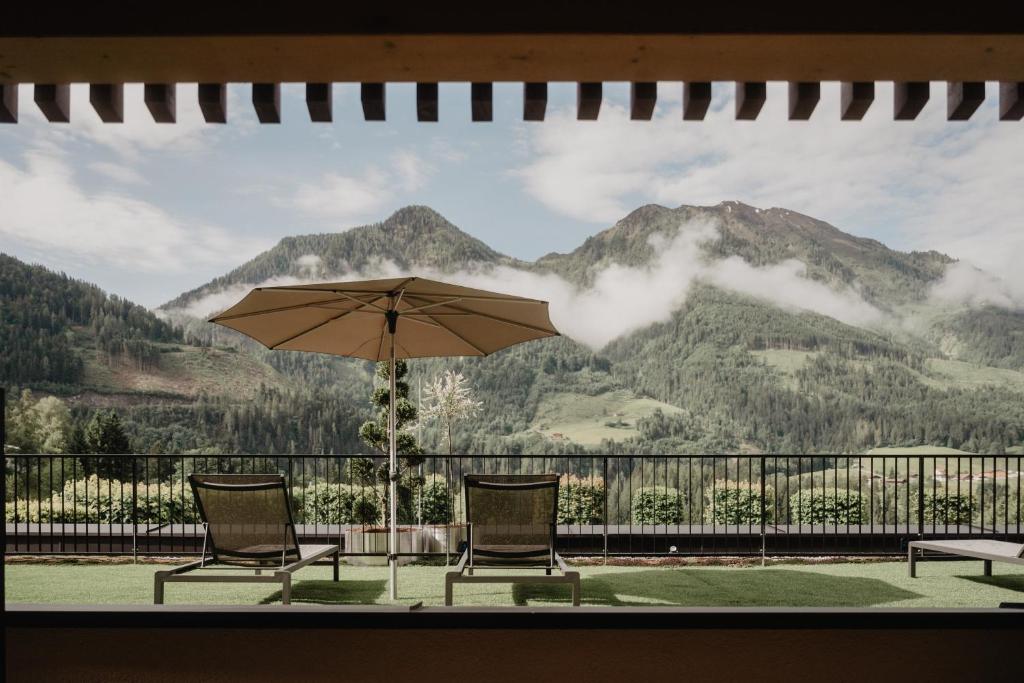 a patio with two chairs and an umbrella at Hotel Berghof - St Johann in Salzburg in Sankt Johann im Pongau