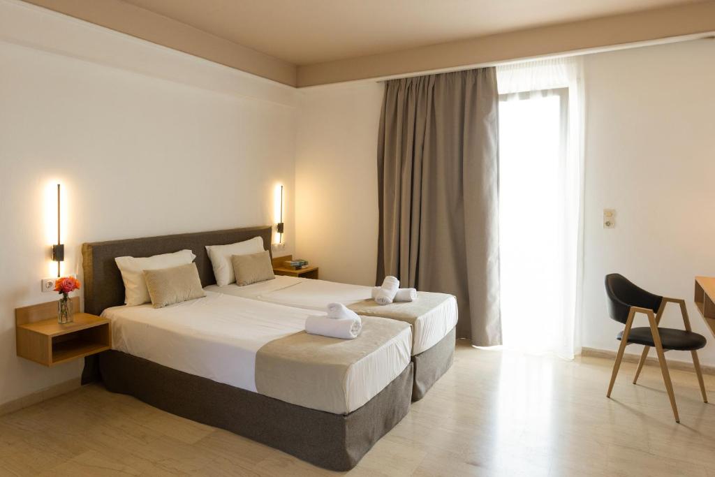 a bedroom with a bed and a chair and a window at Pelagia Bay Hotel in Agia Pelagia