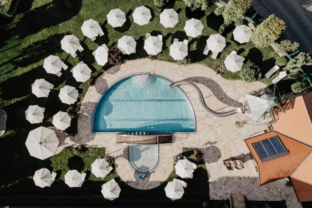 an overhead view of a pool with white umbrellas at Hotel Berghof - St Johann in Salzburg in Sankt Johann im Pongau