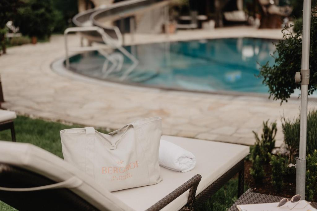 a white bag sitting on a table next to a pool at Hotel Berghof - St Johann in Salzburg in Sankt Johann im Pongau