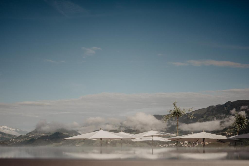 a group of umbrellas on a beach with clouds at Hotel Berghof - St Johann in Salzburg in Sankt Johann im Pongau