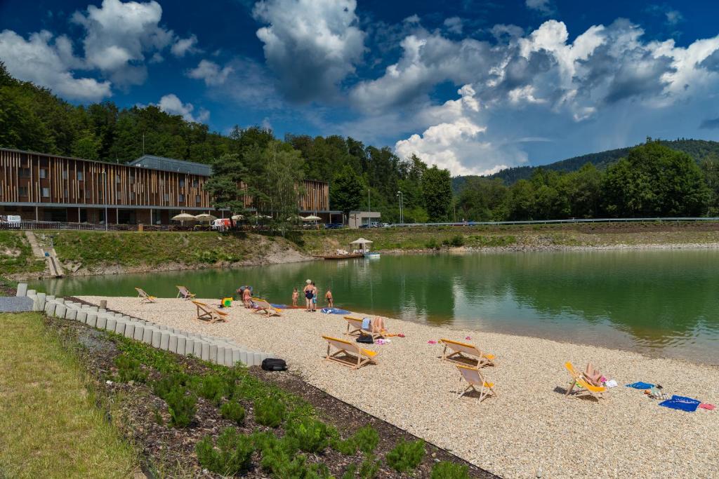 Eine Gruppe von Menschen sitzt an einem Strand neben einem See in der Unterkunft SALAMANDRA Hotel in Banská Štiavnica