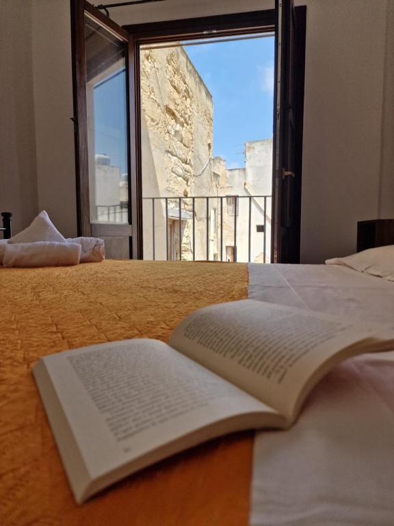 an open book sitting on top of a bed with a window at Giardino Mediterraneo in Trapani