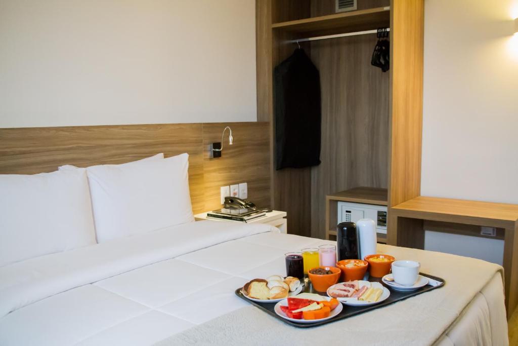 uma bandeja de comida numa cama num quarto de hotel em Intercity Gravataí em Gravataí