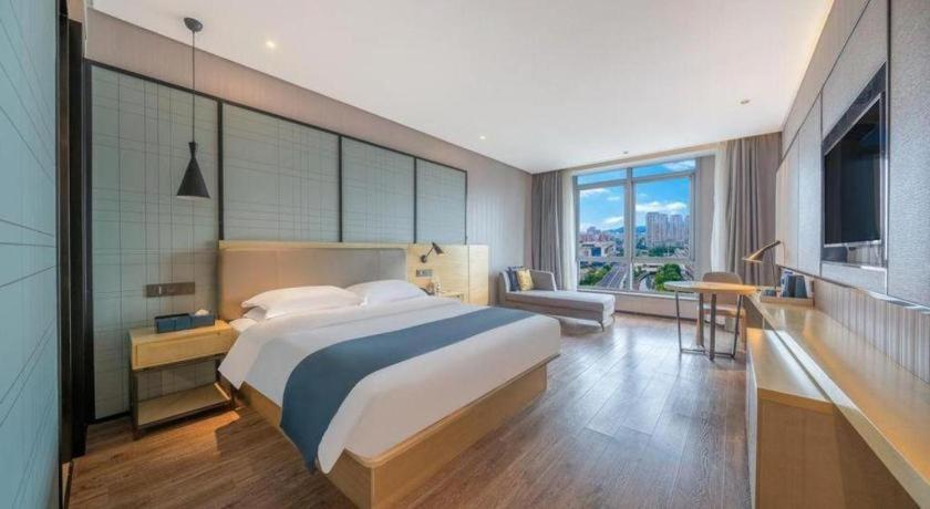 ein Schlafzimmer mit einem großen Bett und einem großen Fenster in der Unterkunft Echarm Hotel Taizhou International Convention and Exhibition Center in Ma-pu-ch'iao