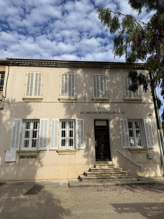 an old white building with a door and stairs at HOTEL JARDINS DE PORQUEROLLES in Porquerolles