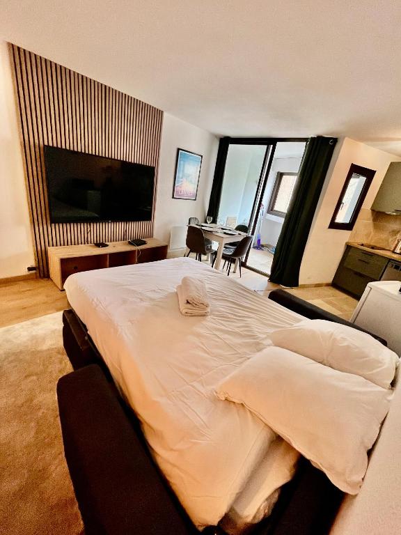 - une chambre avec un grand lit et une table avec des chaises dans l'établissement Cosy a 3 min de la plage avec parking privé, à Cannes