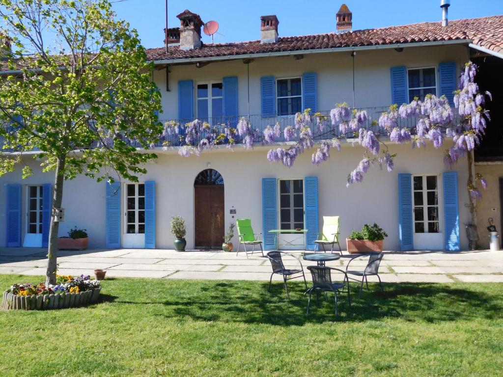 ein Haus mit blauen Fensterläden sowie einem Tisch und Stühlen in der Unterkunft Agriturismo La Tilia in Lequio Tanaro