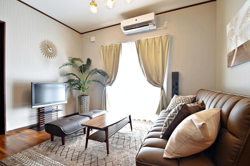 Una sala de estar con un sofá y un televisor. en ゲストハウスえらぶー, en Wadomari