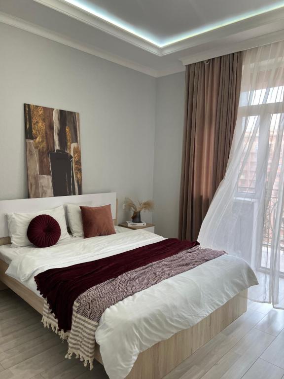 une chambre avec un grand lit avec une grande fenêtre dans l'établissement Двухкомнатная квартира в ЖК Green Plaza, à Aktau