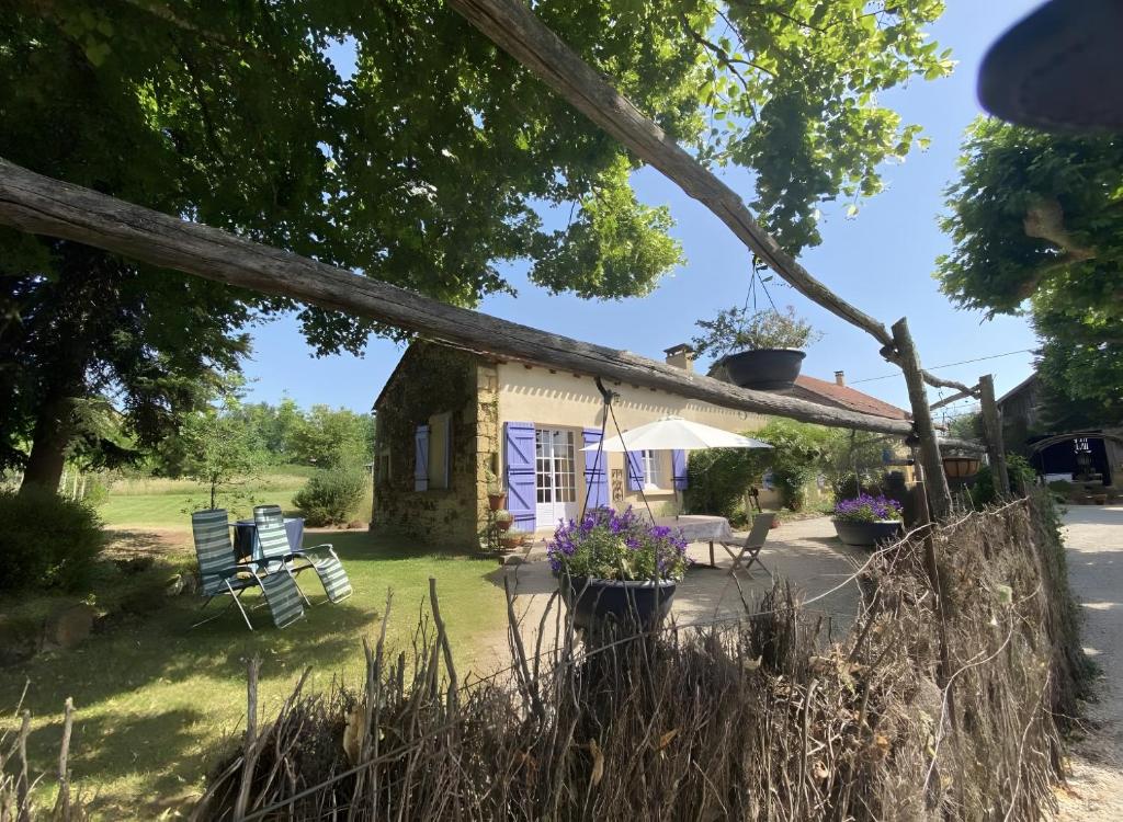 a cottage with a yard with chairs and flowers at Gite La Forge in Le Buisson de Cadouin