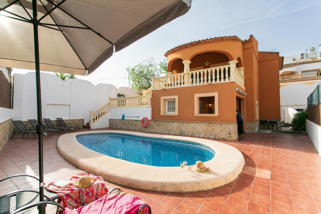 a swimming pool in front of a house with an umbrella at 0301 Villa Maracuya in Balcon del Mar