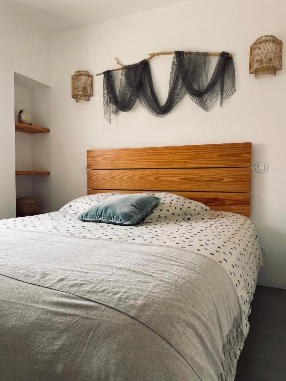 a bed with a wooden headboard and a blue pillow at Casa da Avó in Sesimbra