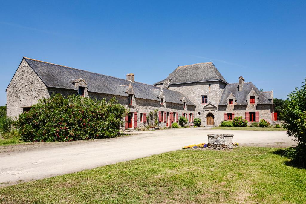 a large stone building with red doors and a driveway at La Ferme du Manoir de Kercassier à Guérande, grand gîte 15 personnes, tarif tout inclus, site exceptionnel dans grand domaine in Guérande