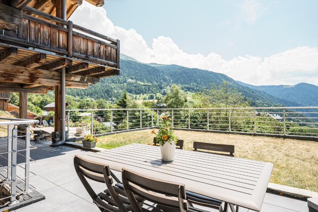 a table and chairs on a patio with mountains in the background at Studio De Charme Montagne in Notre-Dame-du-Pré
