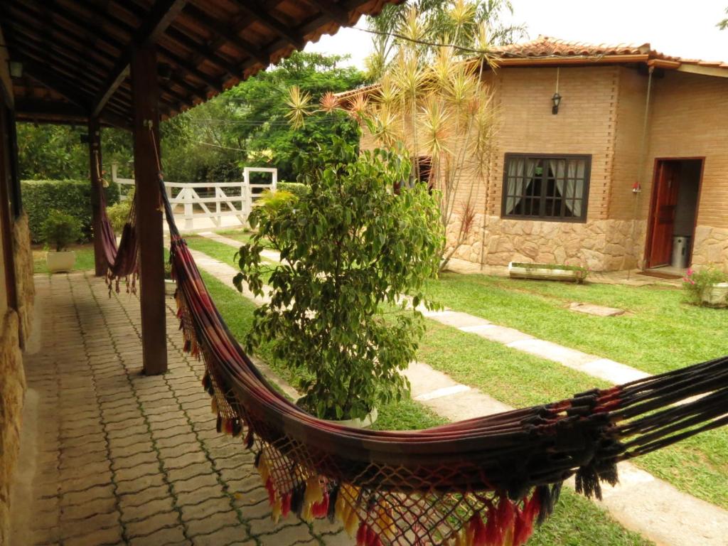 a hammock in front of a house with a yard at Pousada Recanto do João de Barro in Conservatória