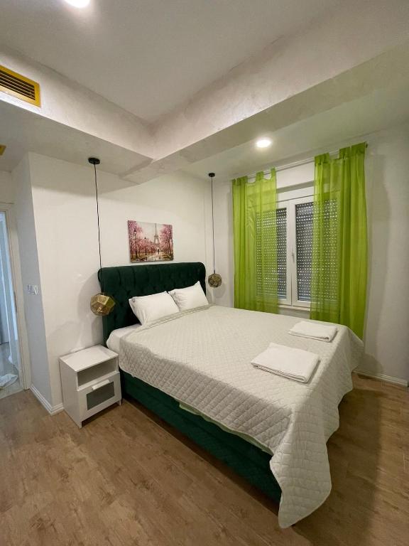 a bedroom with a large bed with green curtains at Deluxe Apartment 2-rooms in Herceg-Novi