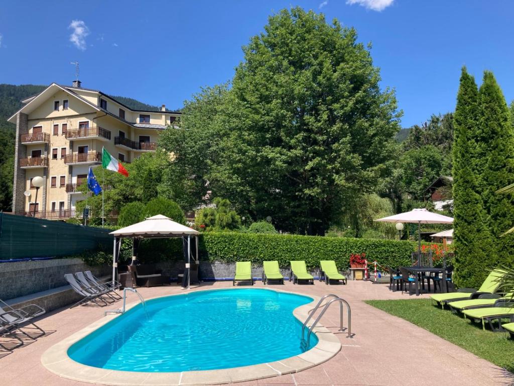 a swimming pool with chairs and a building in the background at RESIDENZA VALLE VIGEZZO in Santa Maria Maggiore