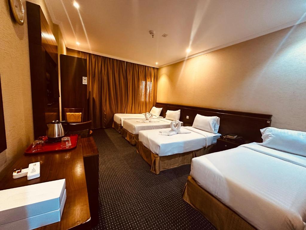 a hotel room with two beds and a table at Diouf Al-Mquam Al-Masy Hotel shuttle service to the Haram in Mecca