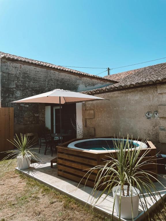 - une piscine avec un parasol à côté d'une maison dans l'établissement Escapade bohème, à Bergerac