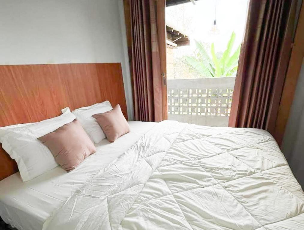 a white bed with pink pillows and a window at RedDoorz Syariah at Budget Guesthouse Sepaku in Sepaku