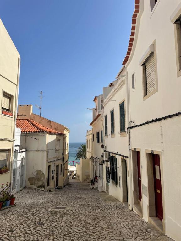 una calle vacía con edificios y el océano en el fondo en Eça 18, en Sesimbra