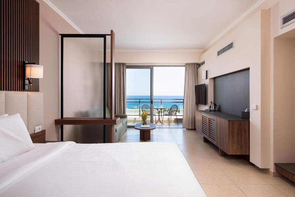 a hotel room with a bed and a view of the ocean at KRESTEN ROYAL Euphoria Resort in Kallithea Rhodes