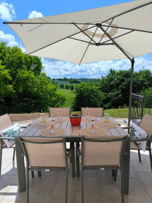 a table with chairs and an umbrella on a patio at la maison de Gaston in Rix
