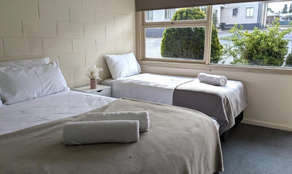 two beds in a room with a window at The Swiss Motel in Cooma