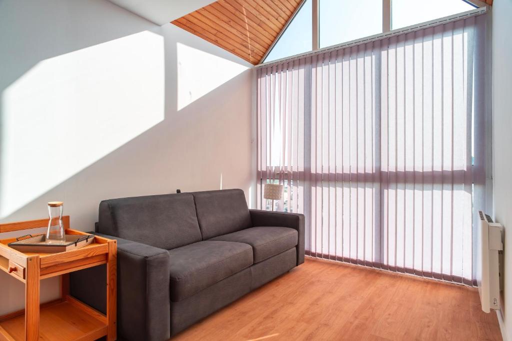 a living room with a couch and a large window at Cap Trinité - Studio avec parking proche port in La Trinité-sur-Mer