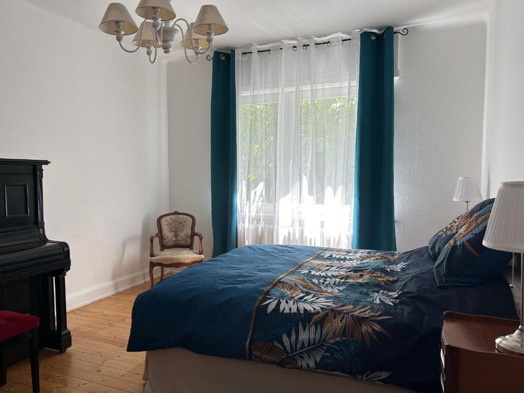 een slaapkamer met een bed en een raam met blauwe gordijnen bij Maison du F'Or in Huningue