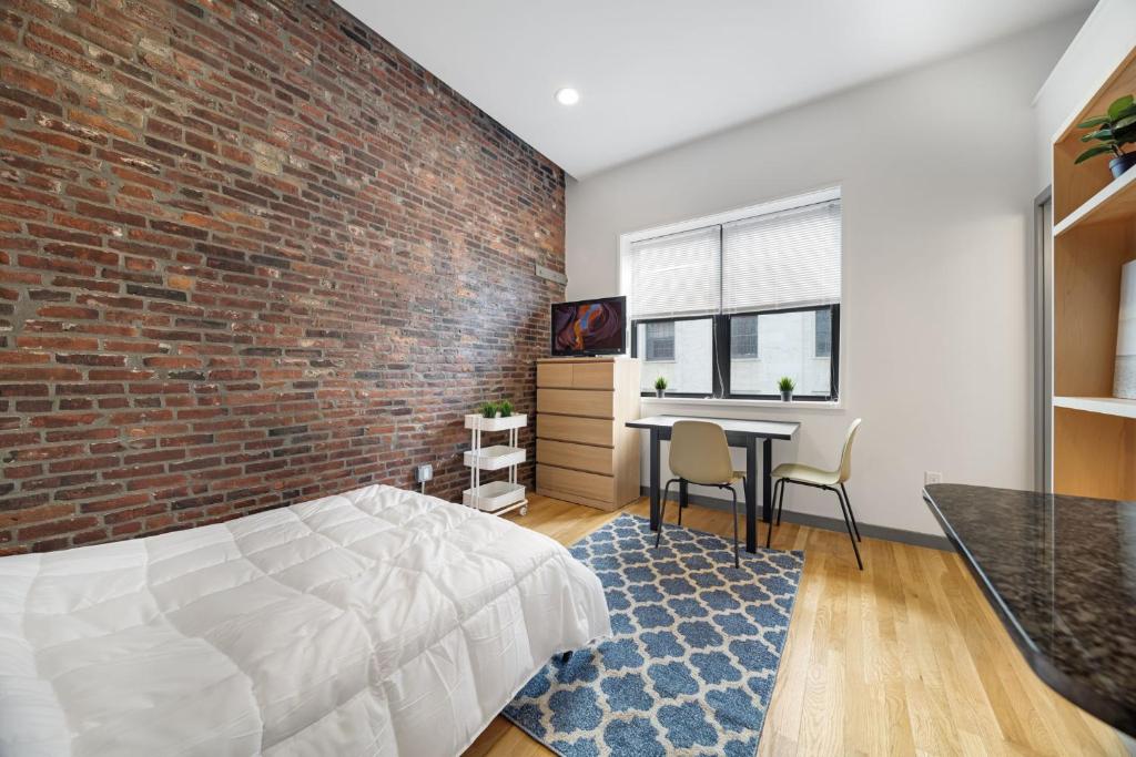 a bedroom with a brick wall and a bed and a desk at Walk to Boston Common, Central Stay in Boston